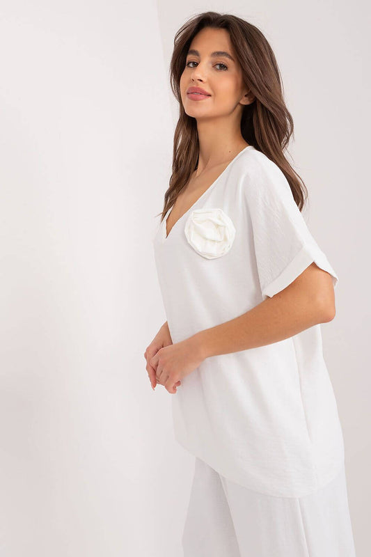 Woman wearing white oversized blouse with flower detail, ideal for comfort and style, perfect for casual outings or work.