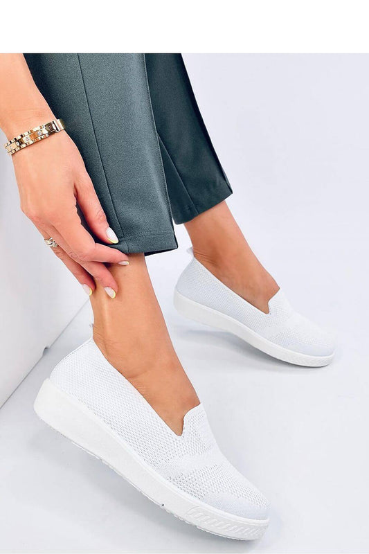 Woman wearing white slip-on sneakers with breathable fabric and slight elevation, showing comfort and style.