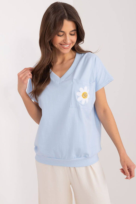 Woman wearing light blue v-neck blouse with daisy design, short sleeves, casual and breathable fabric, perfect for everyday wear.