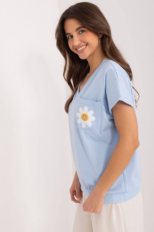 Model wearing a light blue V-neck blouse with daisy pocket detail, perfect for casual outings.