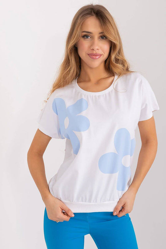 Woman wearing white blouse with blue flower print, short sleeves, and round neckline.