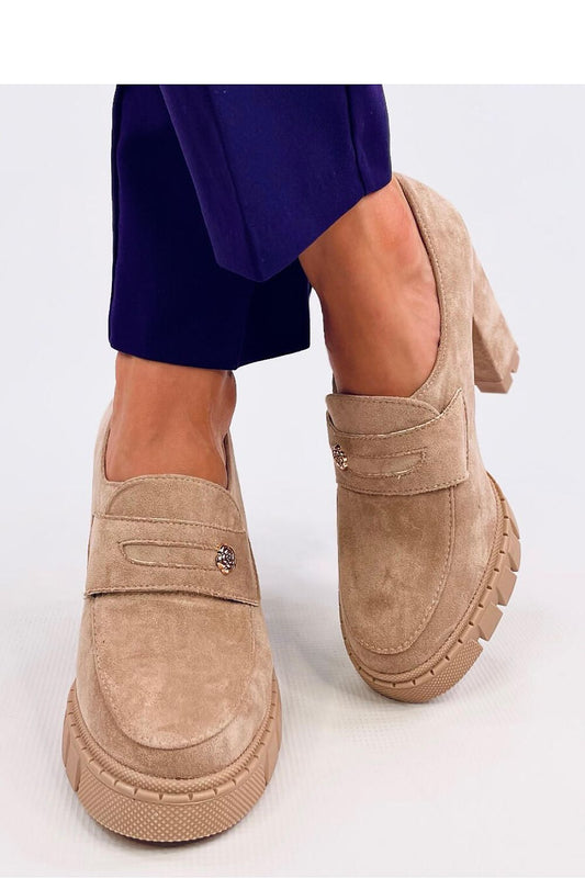 Beige suede platform heels with 10 cm height and 2 cm platform, featuring a delicate flower decoration, worn with purple pants.