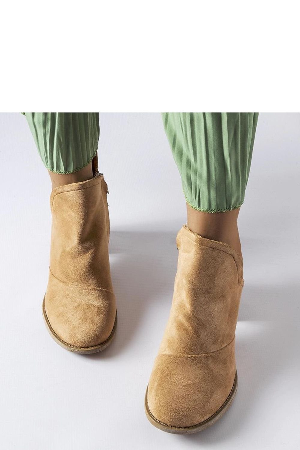 Beige ankle boots with a stylish design, perfect for combining comfort and flair, shown with green pleated pants.