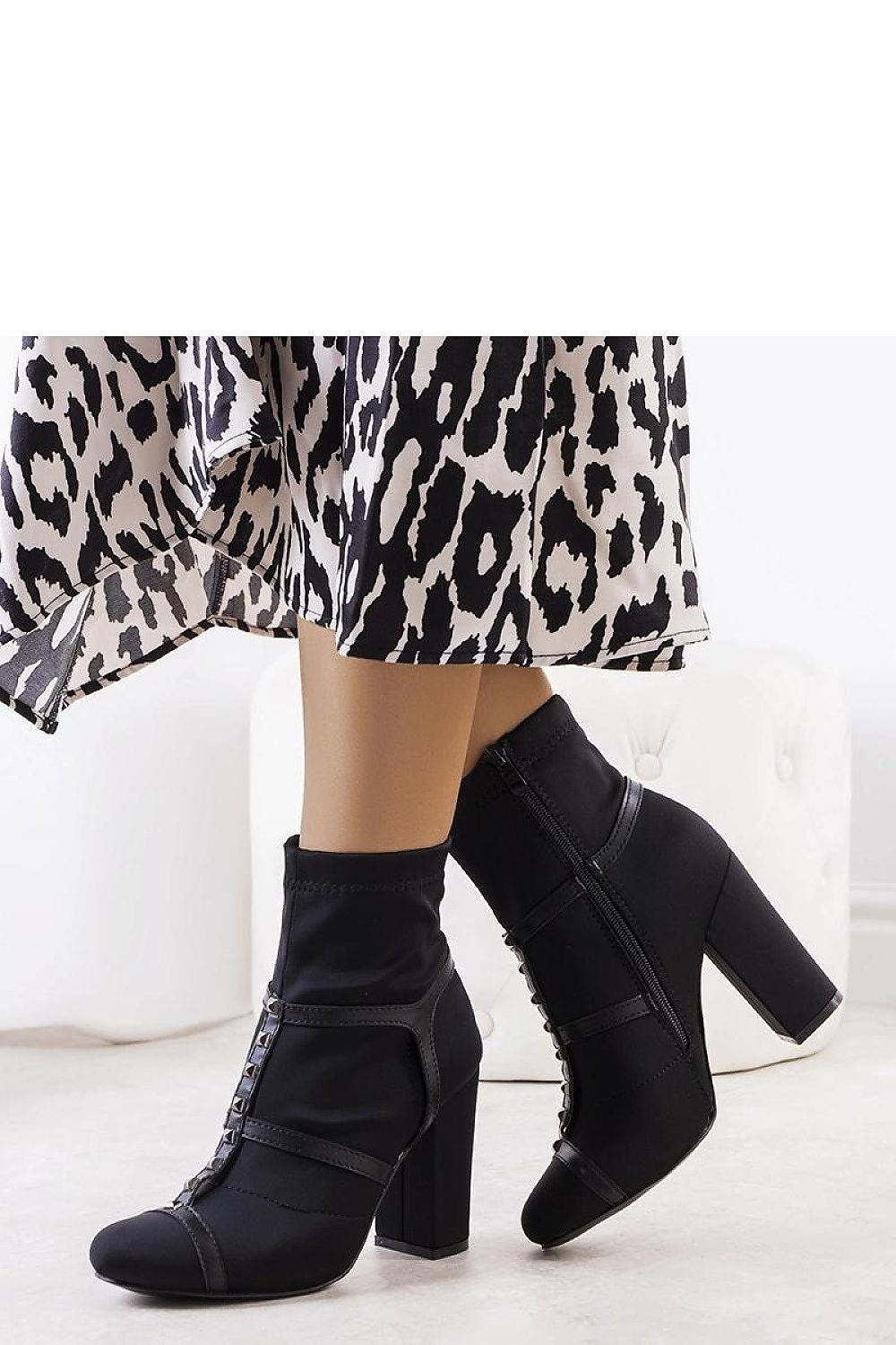 Elegant black high heel ankle boots with eco-leather details complementing a chic, patterned outfit.