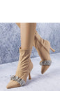 Elegant tan stiletto ankle boots with ruffle detail and side zipper on a textured background.