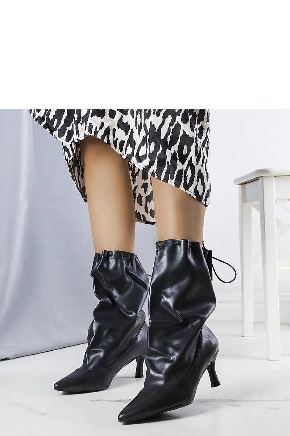 Elegant black eco-leather ankle boots with pointed toe and low heel, paired with animal print dress for a chic look.