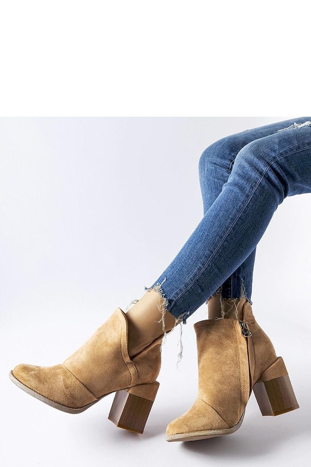 Stylish beige heeled ankle boots with zipper, paired with ripped jeans.