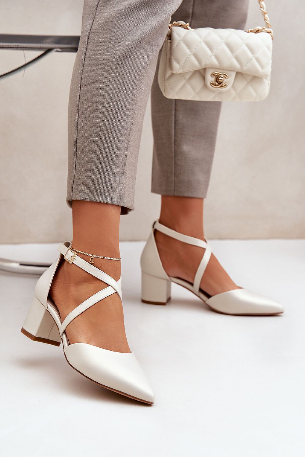 Elegant white block heel shoes with crisscross straps and a quilted handbag, perfect for stylish comfort and sophistication.