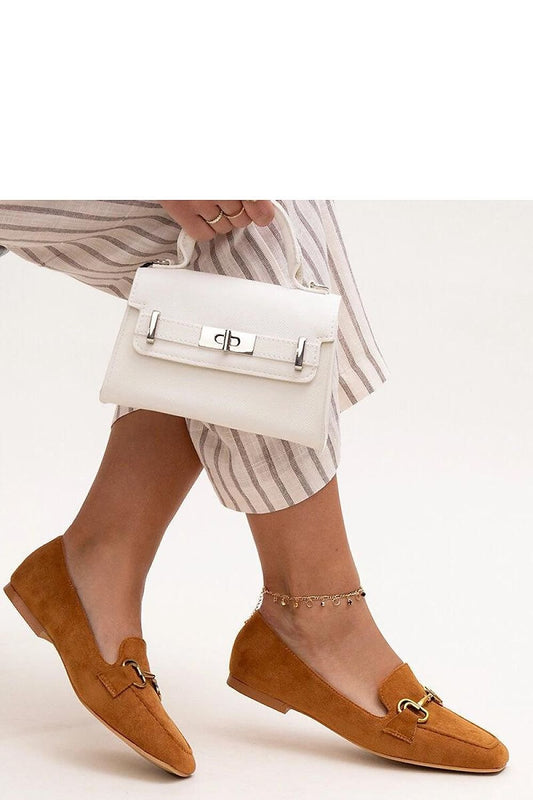 Woman wearing brown Zamari loafers with a stylish striped pant and holding a chic white handbag.