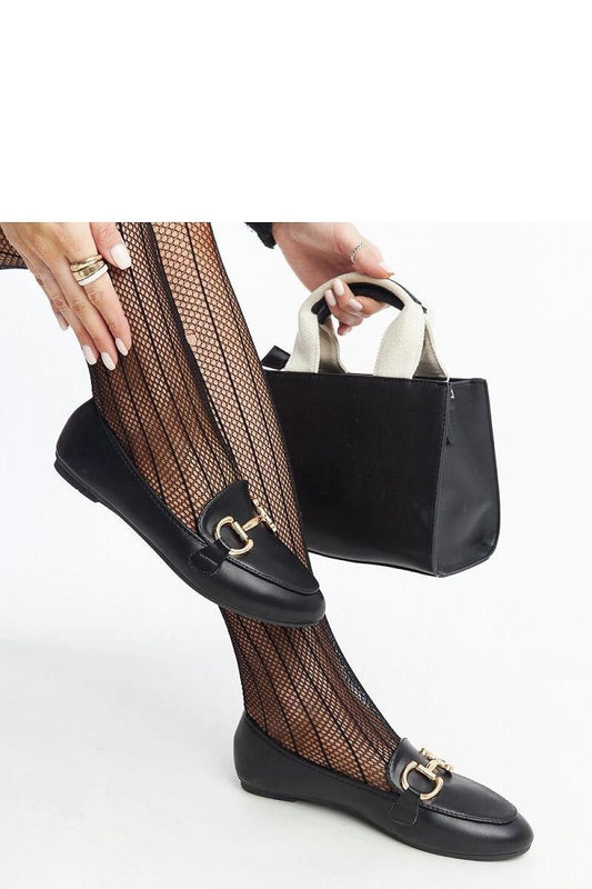 Woman wearing black Tanja buckle loafers with fishnet tights and holding a stylish handbag.