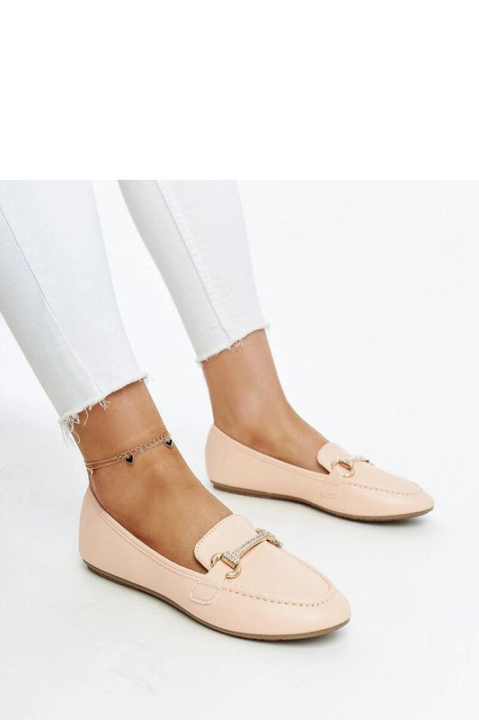 Beige Solea moccasins with decorative front buckle on woman's feet, paired with white jeans, perfect for summer elegance.