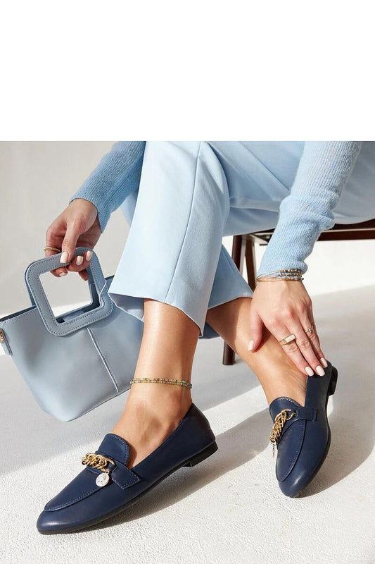 Elegant dark blue Scaletta loafers with decorative chain, perfect for any occasion, shown with light blue pants and matching bag.