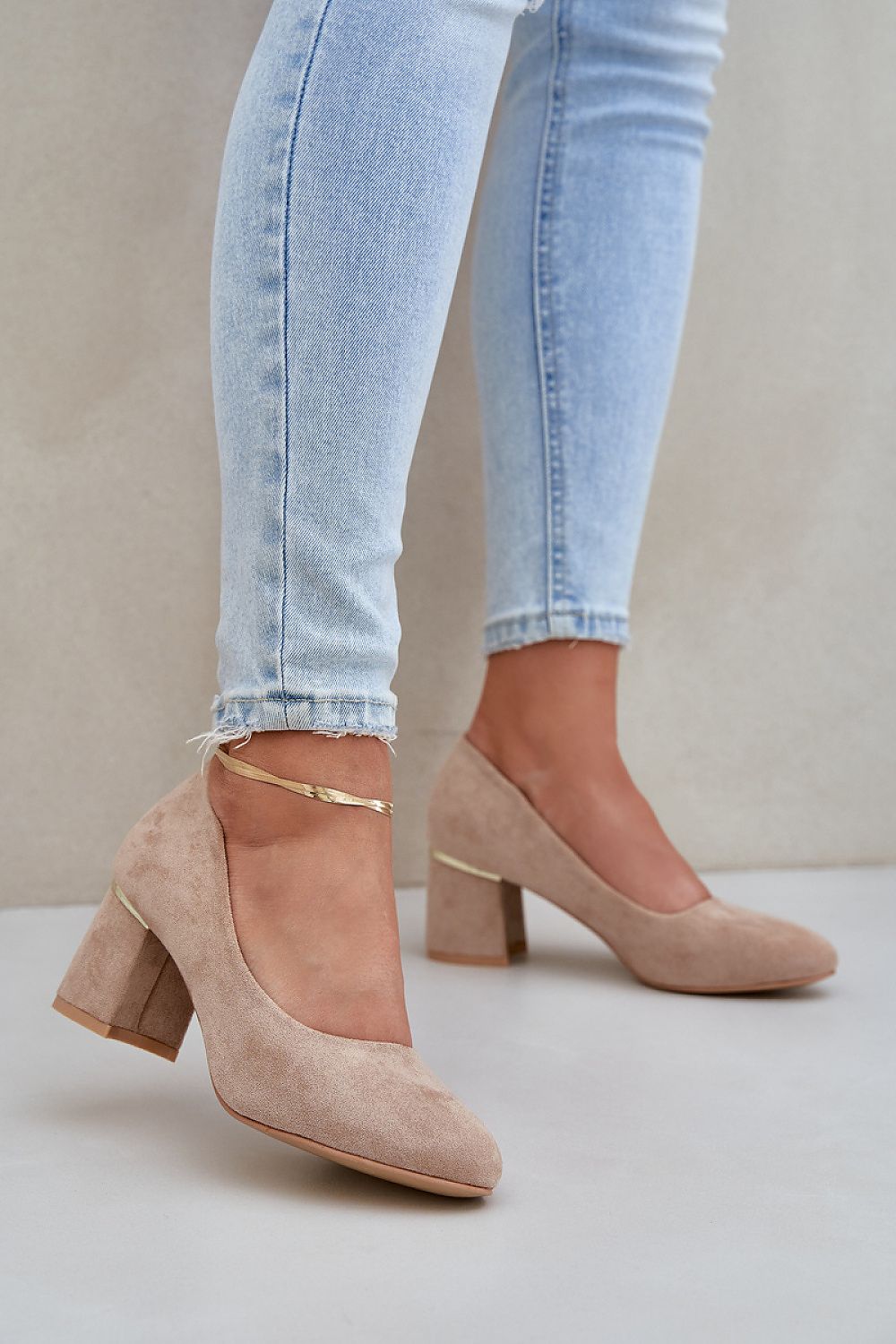 Model wearing beige high heel pumps, block heel with round toe, paired with light wash jeans for a stylish look.