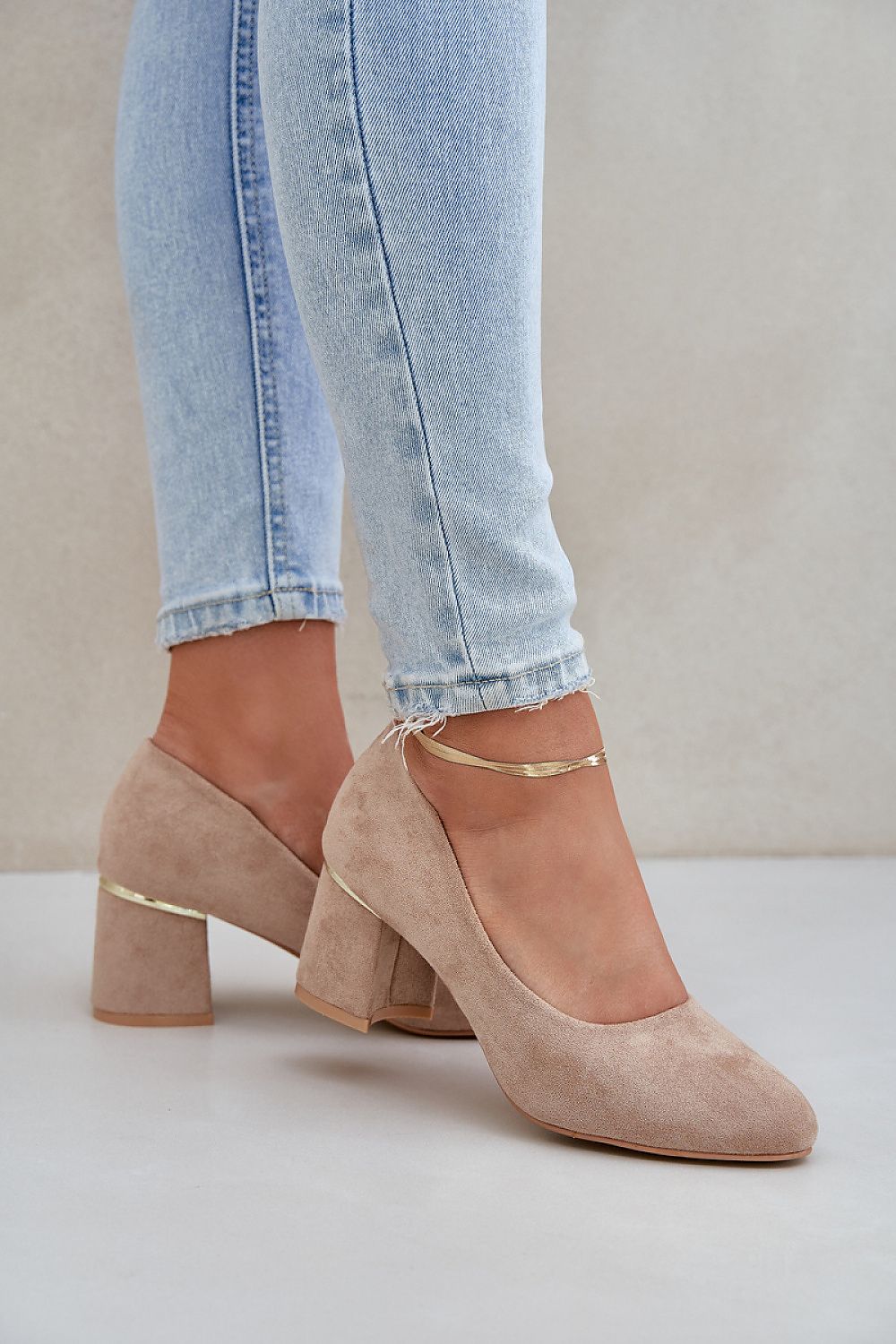 Beige suede high heels with round toe and block heel styled with light jeans.