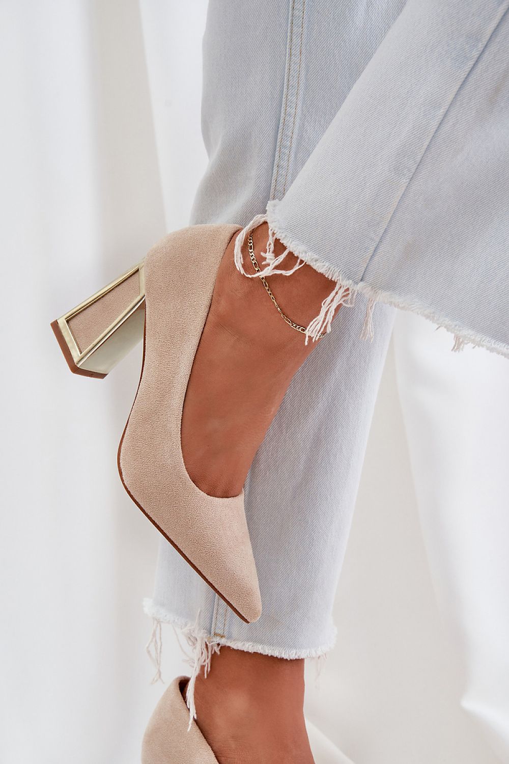 Stylish high-heeled shoe in suede with reflective heel, paired with ripped jeans for a chic look.