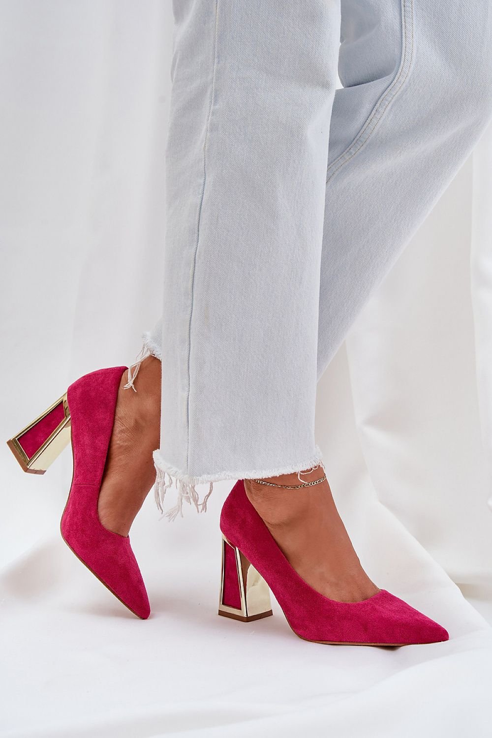 Magenta high heel pump with metallic heel paired with light jeans for a stylish look.