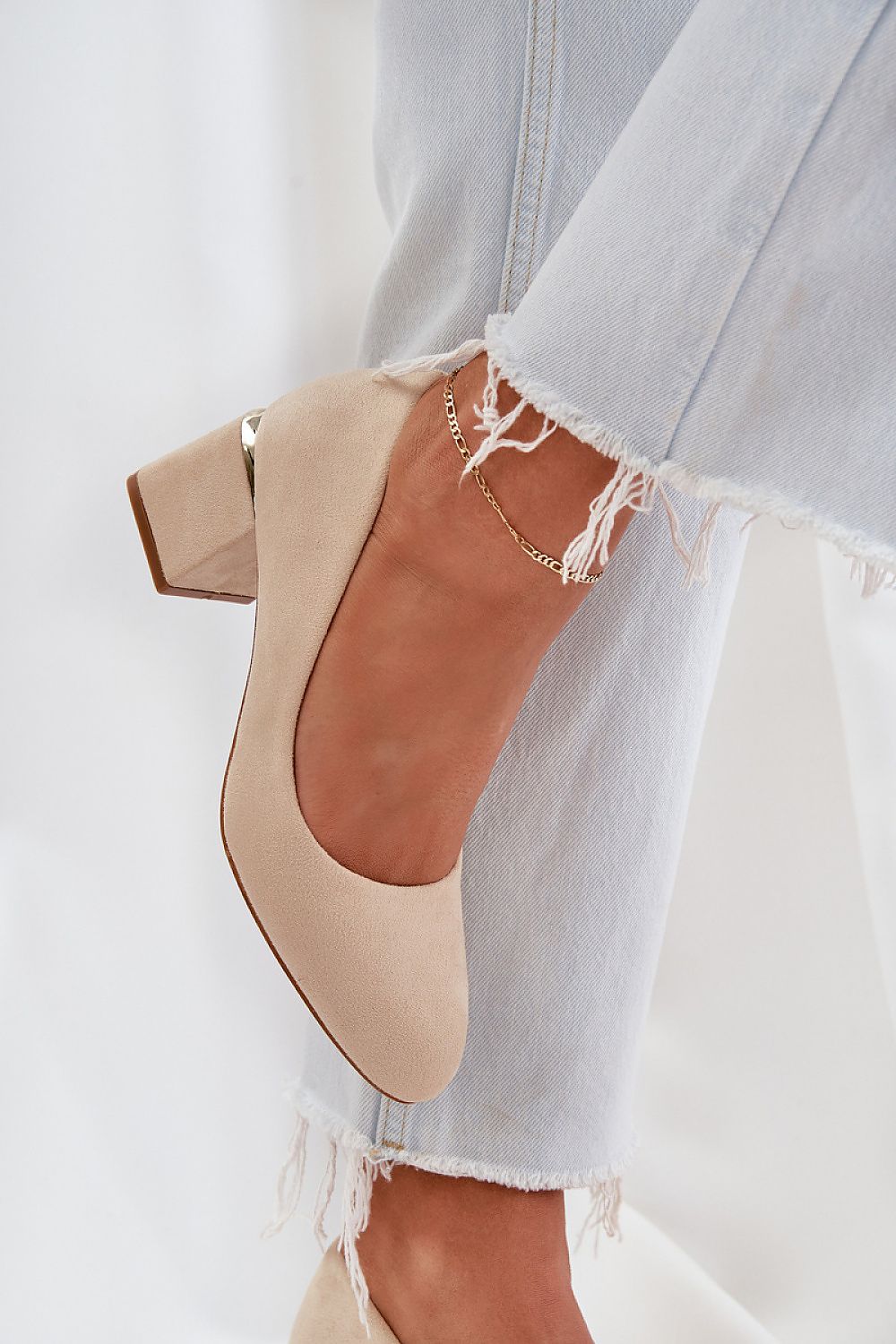 Beige suede high heel shoes with gold detail on block heel, paired with frayed jeans.