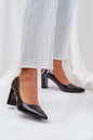 Woman wearing black patent high heel shoes with pointed toes and wide heels, paired with light denim jeans. Perfect for elegant events.