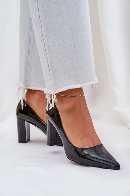 Elegant black patent leather high heels with pointed toes and ankle detail, paired with white frayed jeans.