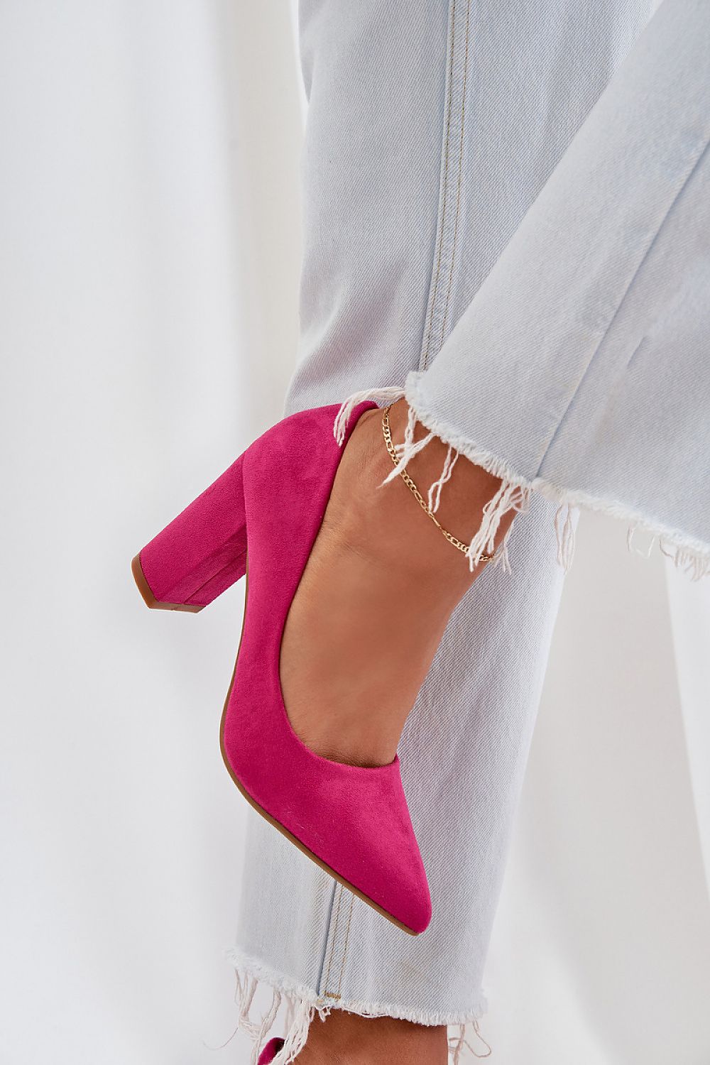 Pink suede high heel shoes paired with frayed jeans, showcasing stylish fashion and comfort.