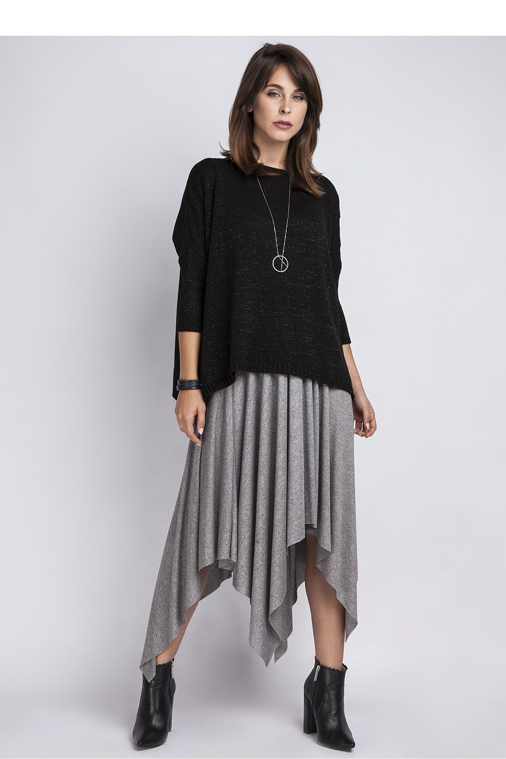 Stylish oversized pullover with silver thread detailing, perfect for chic outings. Model wearing black top and asymmetrical gray skirt with boots.