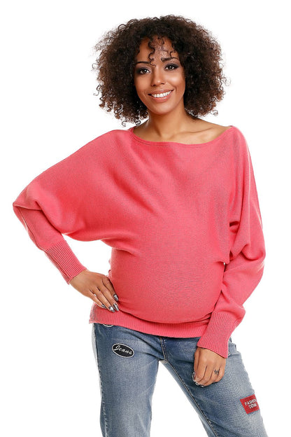 Model wearing oversized pink maternity sweater with boat neckline and long sleeves, showcasing comfortable and stylish pregnancy fashion.