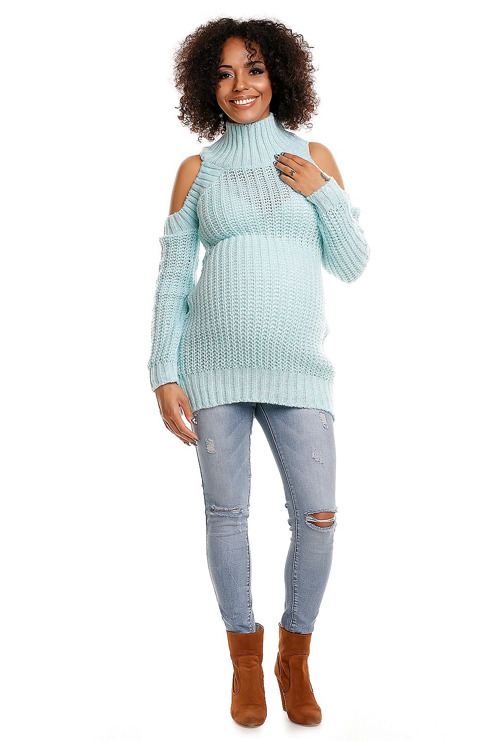 Model wearing a mohair maternity sweater with open shoulders, light blue color, paired with ripped jeans and brown boots, smiling.