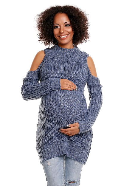 Pregnant woman wearing blue maternity sweater with shoulder cut-outs, smiling and holding her belly, showcasing a stylish and comfortable knit.