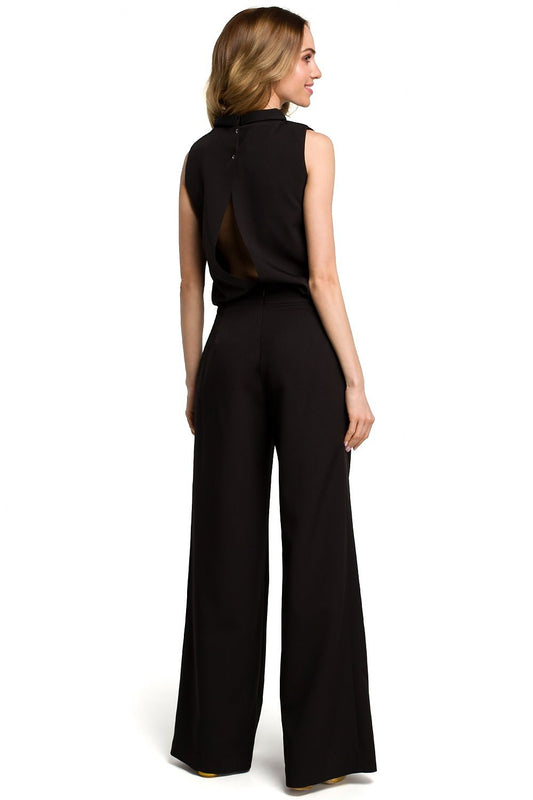 Elegant black jumpsuit with open back and side pockets, showcasing feminine style and comfort. Model wearing Moe Overál 117565.