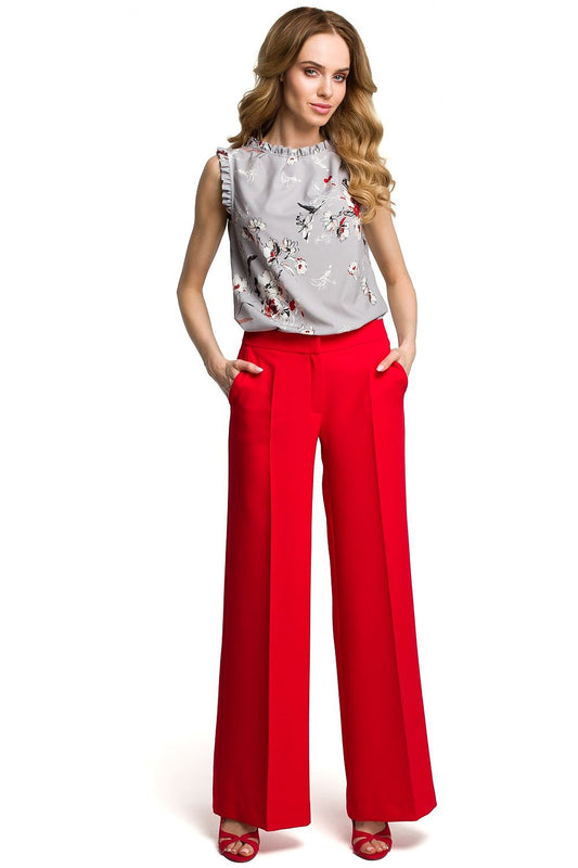 Woman wearing stylish wide-leg red pants with side pockets and zipper closure, paired with a floral top.