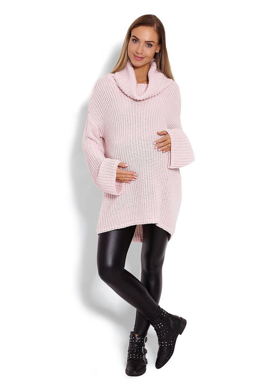 Pregnant woman wearing light pink thick-knit oversized turtleneck pullover by PeeKaBoo, model 122945, with bell sleeves.