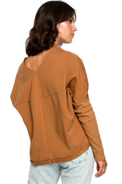 Woman wearing a brown relaxed-fit BeWear pullover with ribbed long sleeves and a draped neckline.