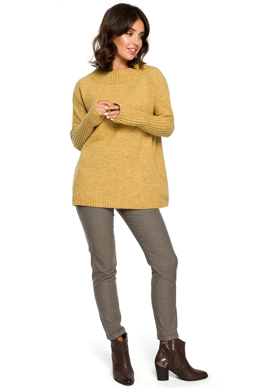 Woman wearing elegant yellow pullover with kimono sleeves, styled with grey pants and brown boots, showcasing chic everyday fashion.