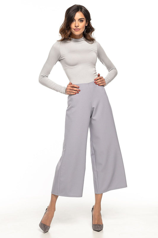 Woman wearing high-waisted wide-leg pants with decorative zipper, inspired by 70s style, perfect for elegant and casual looks.