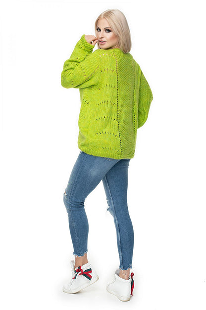 Model wearing green PeeKaBoo pulóver 131600 with intricate open-knit design, paired with blue jeans.