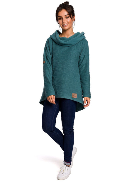 Woman wearing green BeWear Szabadidőfelső model 134537 with asymmetrical cut, ideal for cold seasons, featuring cozy fabric and hood.