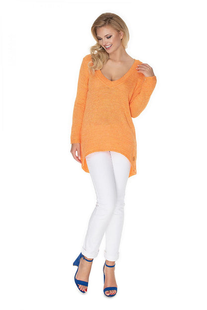 Model wearing an orange PeeKaBoo oversized pullover with asymmetrical cut, paired with white pants and blue heels, showcasing a casual look.