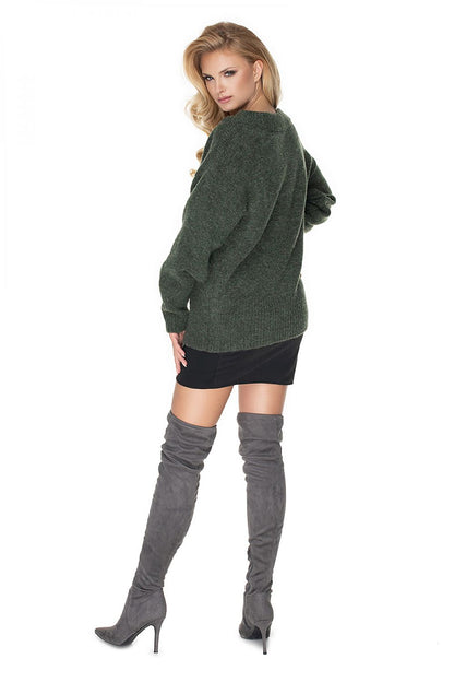 Model wearing forest green oversize pulóver by PeeKaBoo, featuring long sleeves and boat neckline, paired with thigh-high gray boots.