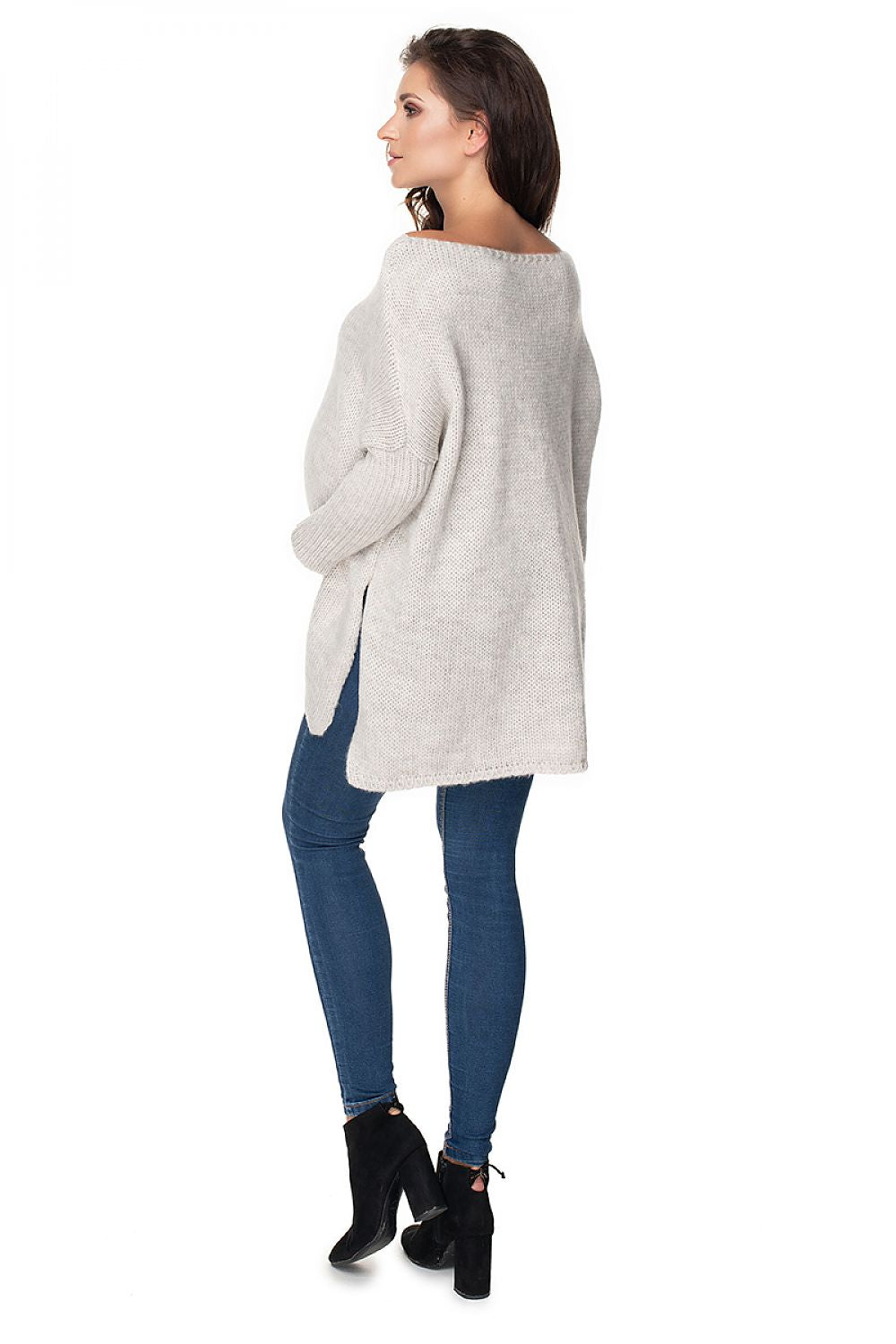 Woman wearing loose maternity pullover model 135981 PeeKaBoo, side slit, long sleeves, gray, paired with jeans and boots.