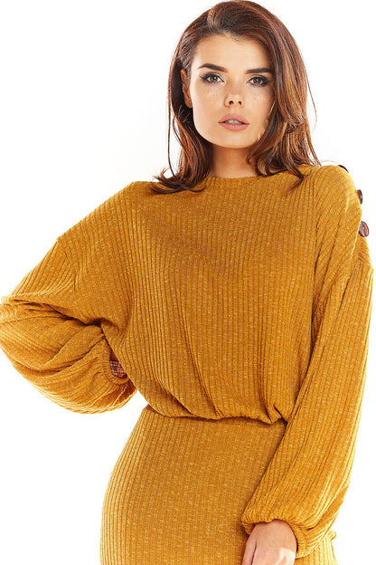 Model wearing mustard oversized pullover with kimono sleeves and decorative shoulder buttons.