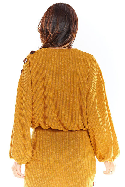 Back view of oversized mustard kimono-style sweater with decorative shoulder buttons, paired with a skirt.