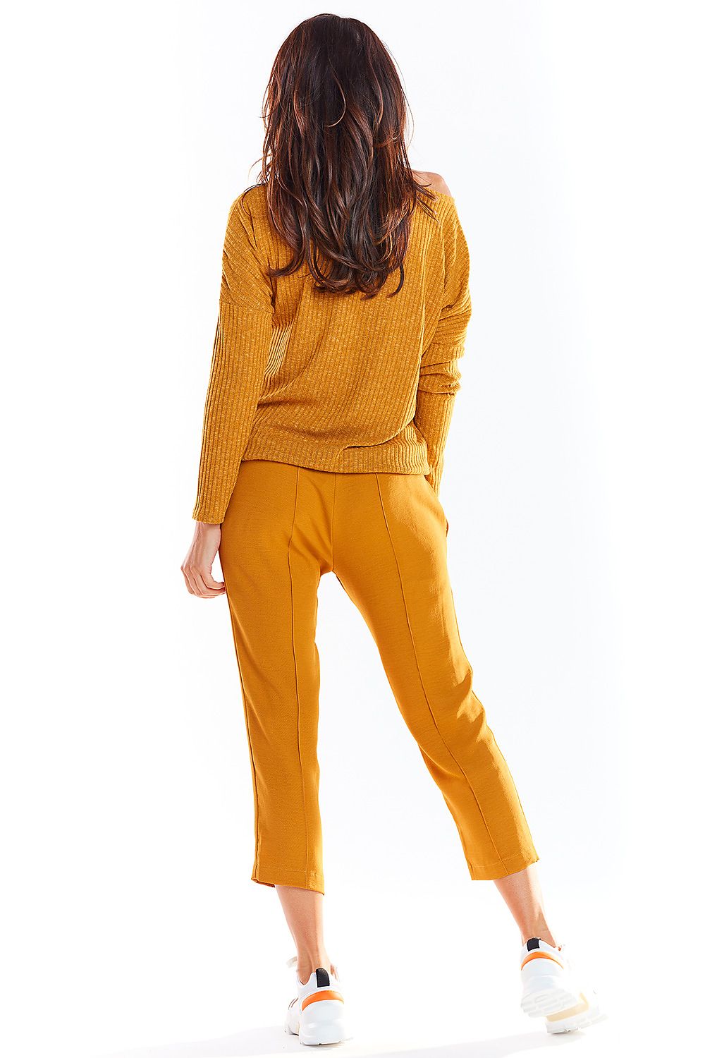 Woman wearing mustard yellow knit sweater and pants, back view