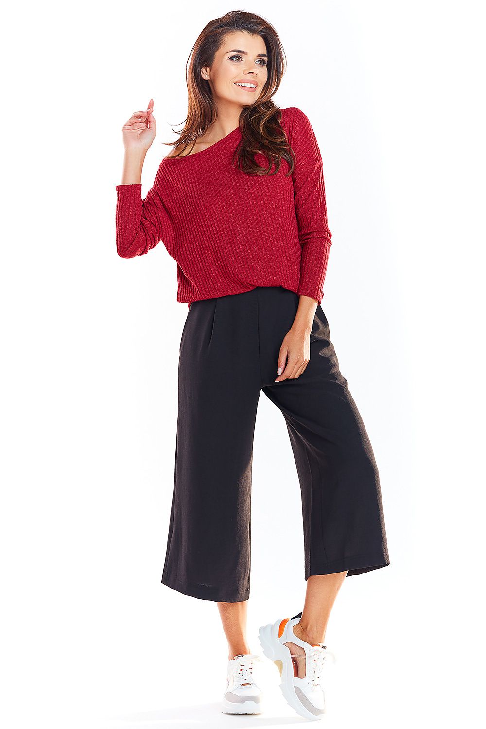 Woman wearing red classic sweater, black culottes, and white sneakers, showcasing Pulóver model 139552 awama.