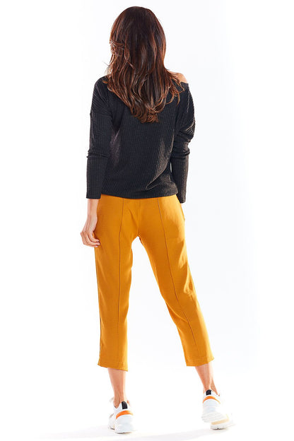 Back view of person in black pullover and mustard pants, showcasing casual fall fashion.