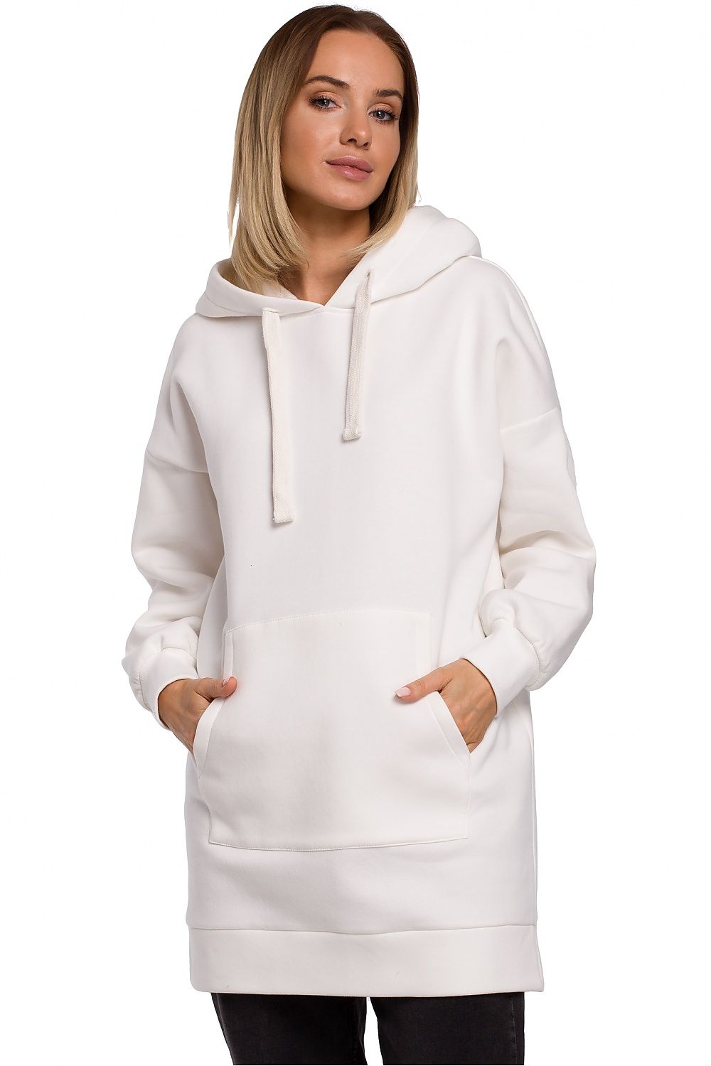 Oversized white hoodie with pockets and hood, perfect for layering, modeled by a person standing with hands in pockets.