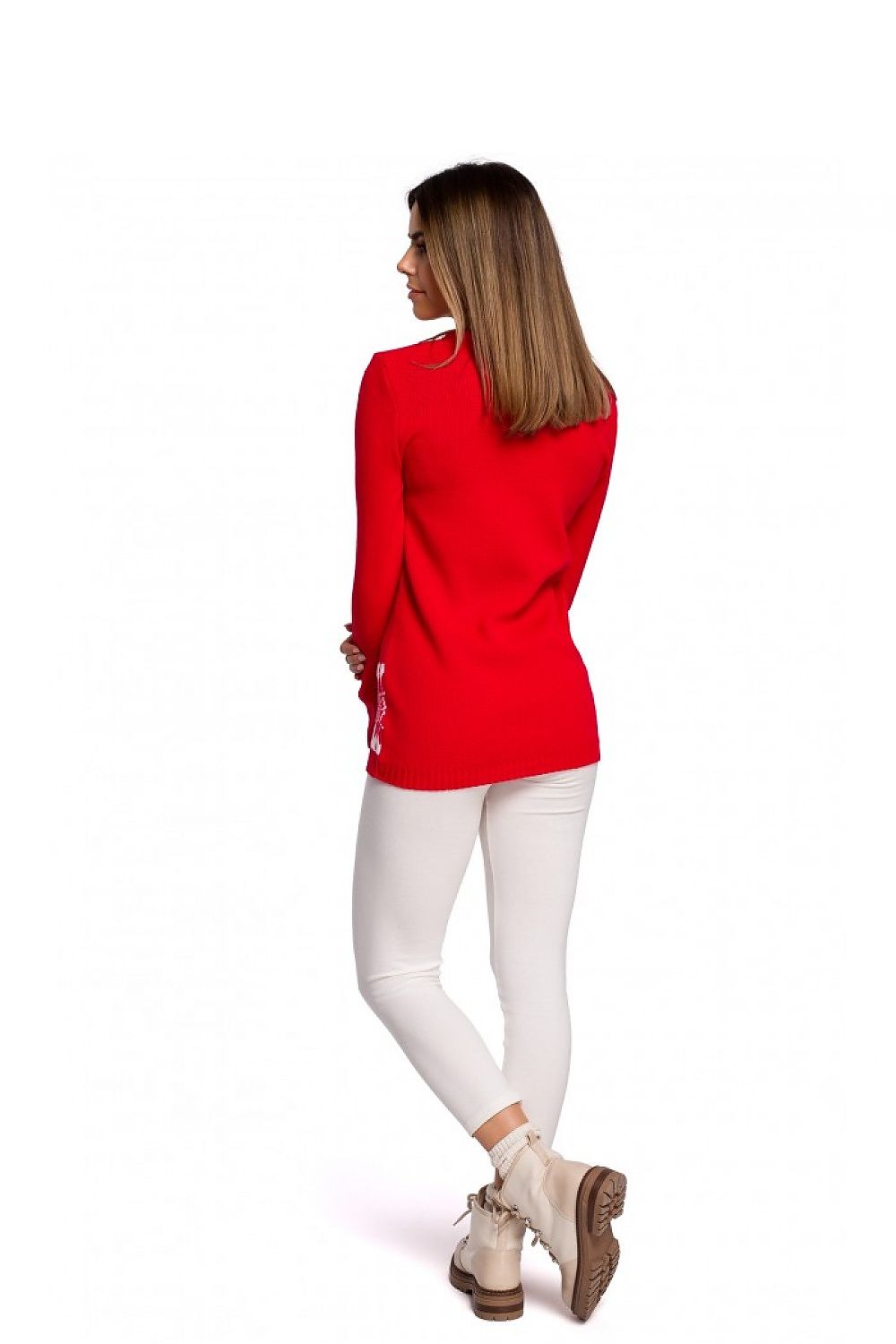 Woman in festive red Christmas sweater with reindeer motif, paired with white pants and boots, model 150212 Moe. Limited edition, 100% acrylic.