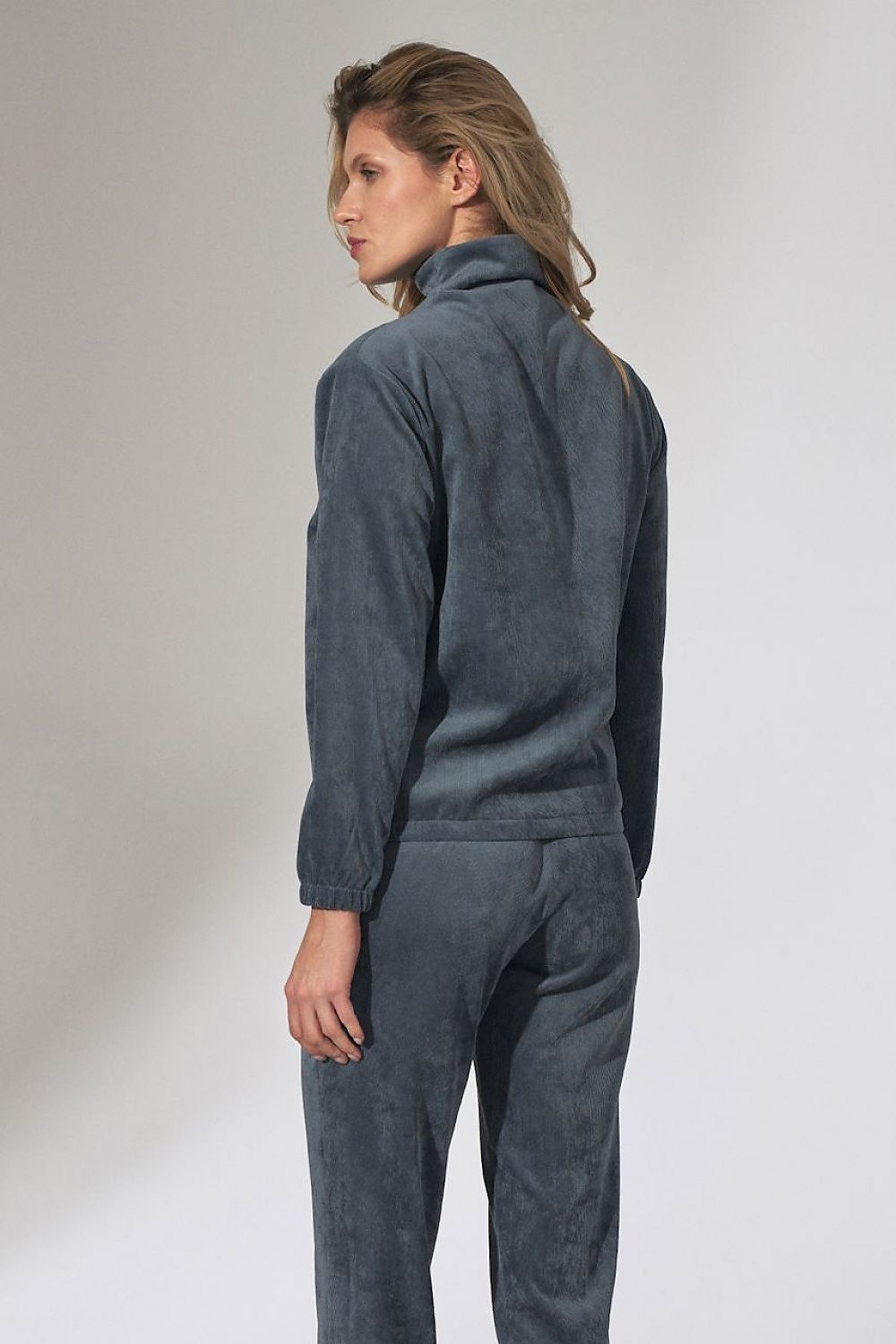 Model wearing a stylish grey tracksuit with a high collar, viewed from the back, showcasing the comfortable and trendy design.