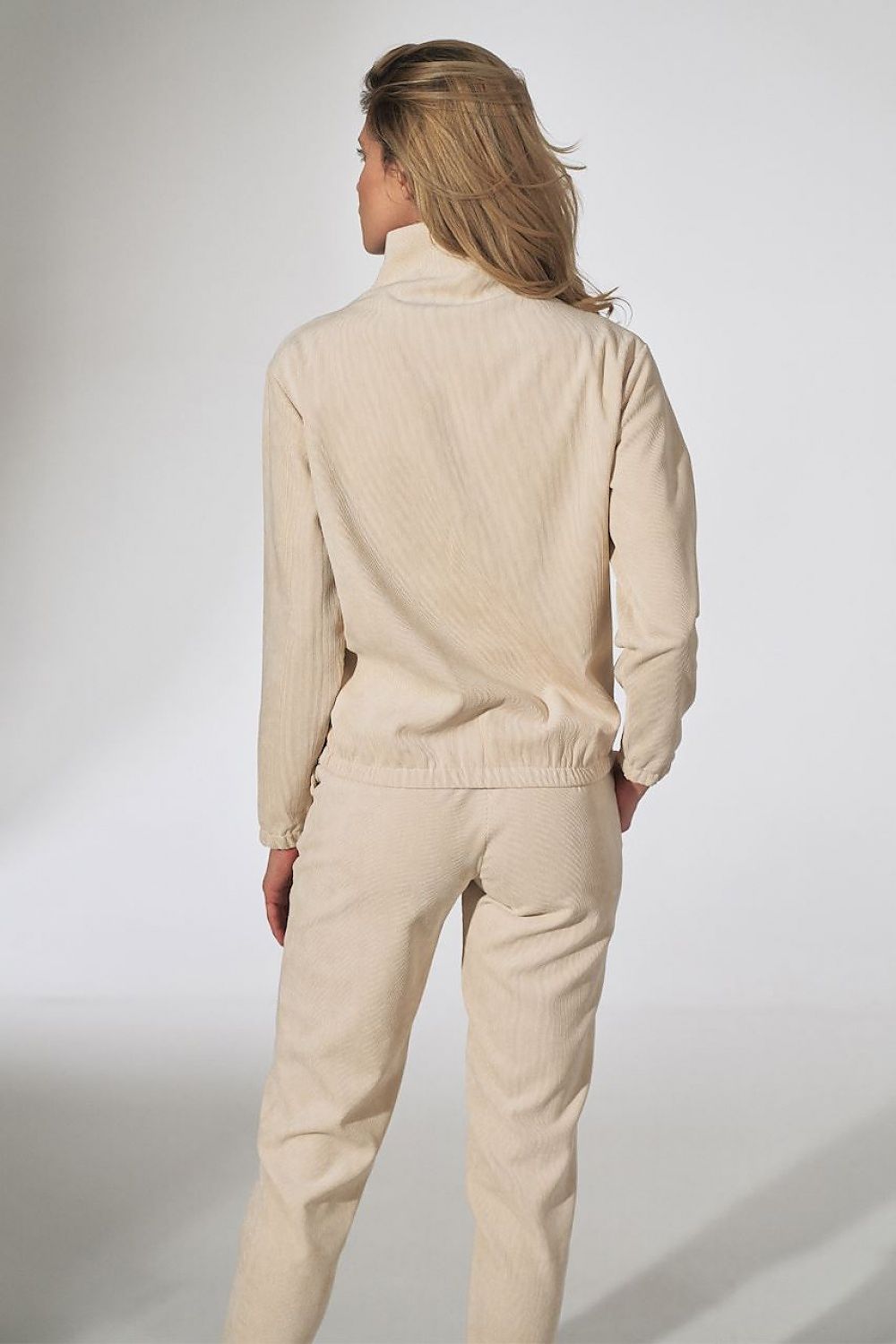 Woman wearing cream corduroy jacket and pants set, viewed from the back, featuring an elastic waistband.