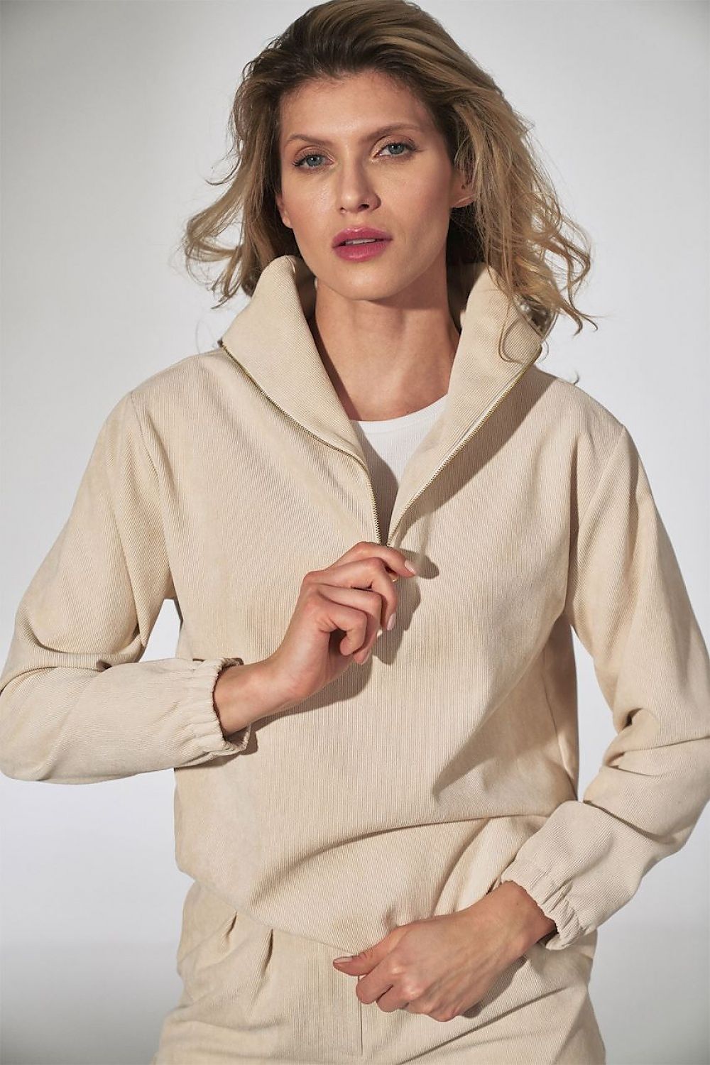 Model wearing a stylish taupe pullover with a high collar and casual fit, perfect for a chic yet comfortable look.