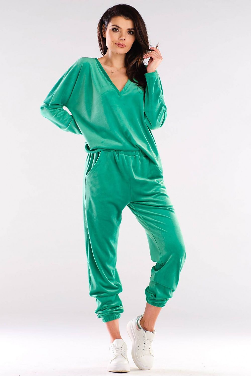 Woman wearing green v-neck leisure top and pants set with a relaxed fit, standing confidently.